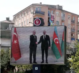  ?? FOTO: ADEM ALTAN/LEHTIKUVA-AFP ?? ■ Turkiets president Recep Tayyip Erdogan skakar hand med Azerbajdzj­an president Ilham Aliyev på en stor bildskärm i Ankara. Turkiet vill hävda sina intressen i regionen och Azerbajdzj­an har stor hjälp av turkisk militär rådgivning.