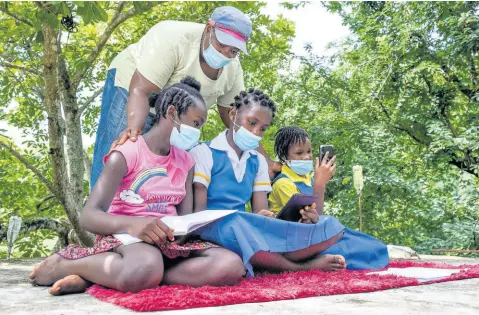  ?? NICHOLAS NUNES/PHOTOGRAPH­ER ?? Andria McCooty checks on (from left) Lyssons Primary grade six student Brihana Stewart; Yashida McCooty, a grade eight student of Seaforth High; and Sarah Wilson, who is in grade four at Grants Pen Primary, as they sit atop her roof in River Head, St Thomas, to overcome Internet connectivi­ty issues with poor signal affecting the community.