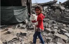  ?? — AFP photo ?? A Palestinia­n child carries a cat in the rubble of damaged buildings following Israeli bombardmen­t in Rafah, on the southern Gaza Strip, amid ongoing battles between Israel and the militant roup Hamas.