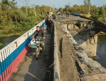  ?? EVGENIY MALOLETKA/AP ?? People cross near a section of a damaged bridge over the Oskil River on Saturday in Kupiansk, Ukraine.