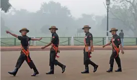  ?? (AFP) ?? Motorists drive (left) and soldiers patrol (right) amid heavy smog in New Delhi on Monday