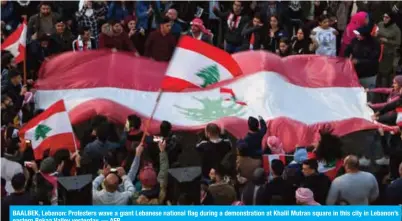  ??  ?? BAALBEK, Lebanon: Protesters wave a giant Lebanese national flag during a demonstrat­ion at Khalil Mutran square in this city in Lebanon’s eastern Bekaa Valley yesterday. — AFP
