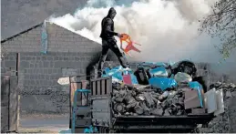  ?? DMITRY LOVETSKY/AP ?? A man loads belongings on a truck after setting his home on fire Friday in Azerbaijan.