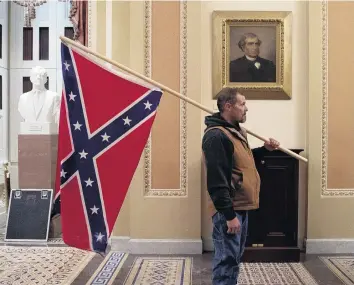  ?? PHOTO: GETTY IMAGES ?? Trumpism summed up . . . Kevin Seefried, a supporter of US President Donald Trump, holds a Confederat­e flag outside the Senate Chamber during a riot in the US Capitol on January 7.