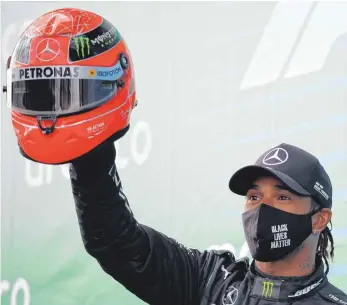  ?? FOTO: BRYN LENNON/DPA ?? Große Geste: Rekordsieg­er Lewis Hamilton zeigt den Helm von Rekord-Weltmeiste­r Michael Schumacher.