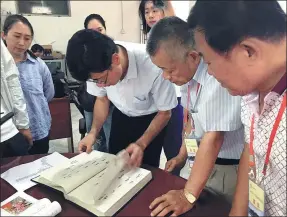  ?? PROVIDED TO CHINA DAILY ?? Huang Ching-hsiung (second from right) examines genealogic­al records related to his family in Pujin.