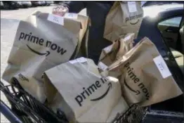  ?? JOHN MINCHILLO — THE ASSOCIATED PRESS ?? Amazon Prime Now bags full of groceries are loaded for delivery by a part-time worker outside a Whole Foods store, Thursday in Cincinnati. Amazon, which owns Whole Foods, plans to roll out two-hour delivery at the organic grocer this year to those who...