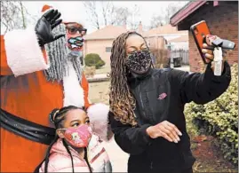  ??  ?? Dreezy Claus takes a selfie with Toya Jones-West and her daughter ChaseWest, 6, at a community event Dec. 5 in Chicago.