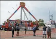  ?? ASSOCIATED PRESS FILE ?? Passers by look at the fire ball ride as Ohio State Highway Patrol troopers stand guard at the Ohio State Fair in Columbus on July 27, 2017. The fair closed rides one day after Tyler Jarrell, 18, was killed and seven other people were injured when the...