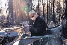  ??  ?? Jerry Ginter sifts through the remnants of his burned-out home looking for a set of treasured knives.