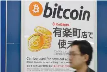  ??  ?? THIS PICTURE taken in April shows a man walking past a signboard informing customers that Bitcoin can be used for payment at a store in Tokyo.