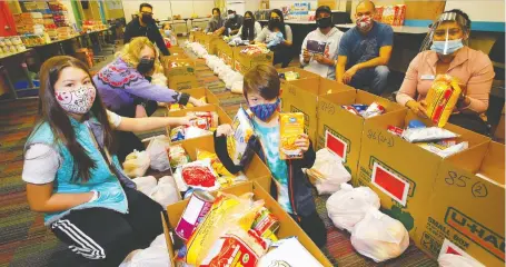  ?? DARREN MAKOWICHUK ?? Volunteers and families sort items at the Centre for Newcomers — in partnershi­p with the Calgary East Zone Newcomers Collaborat­ive — which has delivered numerous food hampers in an effort to help create a greater sense of food security for those in need.