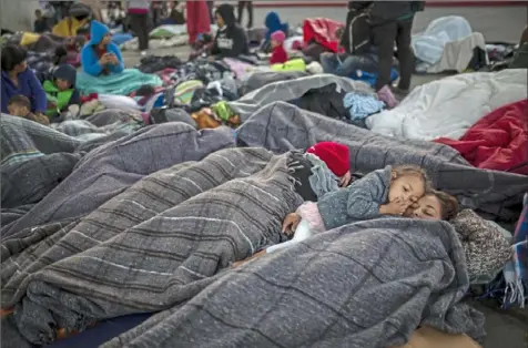 ?? Rodrigo Abd/Associated Press ?? Julia Romero, 4, snuggles with her mother, Lurvin Sarmiento, from Honduras, as they wake from their sleep Friday at the Chaparral border crossing in Tijuana, Mexico.