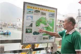  ??  ?? HONG KONG: Tour boat operator Wong Yung-kan pointing out where the famous pink dolphins are found in the waters around Tai O.
