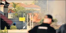  ?? Picture: EUGENE COETZEE ?? CLOSE CALL: Firefighte­rs keep watch as a bush fire gets close to homes in Gomery Avenue, Summerstra­nd, yesterday