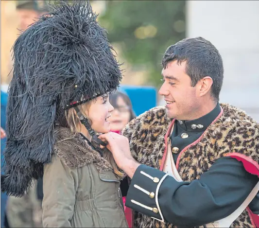  ??  ?? Fusilier Steven Mair, 25, from Glasgow, fastens his bearskin to daughter Skye, six, as Royal Regiment of Scotland soldiers spend time with family yesterday following a six-month tour of duty in Iraq, South Sudan and Cyprus, ahead of a reception at City Chambers