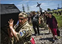  ?? ?? Unfortunat­ely, since the invasion began, funerals occur daily around Ukraine. Soldiers carry the caskets of their fallen comrades to their gravesites.