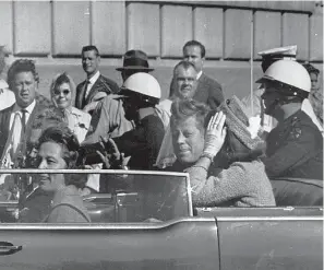  ?? Photos via Associated Press ?? leftPresid­ent John F. Kennedy rides in a motorcade with his wife, Jacqueline, moments before he was shot and killed Nov. 22, 1963, in Dallas. Texas Governor and Mrs. John Connally are also in the car. Video footage of Kennedy’s motorcade as it drove slowly through Dallas marked an entire generation and has been the source of plenty of conspiracy theories since.