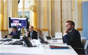  ?? GONZALO FUENTES/POOL VIA AP ?? French President Emmanuel Macron, right, listens as he attends with French Foreign Minister Jean-Yves le Drian, center, an internatio­nal videoconfe­rence on vaccinatio­n at the Elysee Palace on Monday.