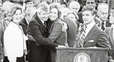  ?? ?? Kentucky Gov. John Y. Brown Jr. (second from left) hugs his wife, TV celebrity Phyllis George, after being sworn in as
