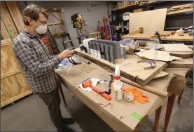  ?? (NWA Democrat-Gazette/David Gottschalk) ?? Vincent Edwards, an instructor in the School of Art, attaches the face shield to a headband Friday in the wood shop at the University of Arkansas’ sculpture studio in Fayettevil­le. The headbands are produced with the use of a 3D printer and are donated to hospital workers and first-responders. Go to nwaonline.com/200526Dail­y/ for today’s photo gallery.