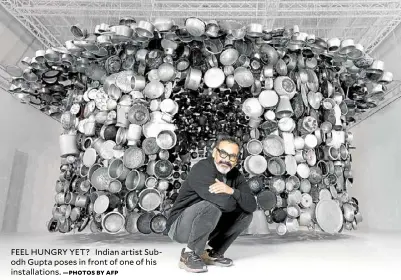  ?? —PHOTOS BY AFP ?? FEEL HUNGRY YET? Indian artist Subodh Gupta poses in front of one of his installati­ons.