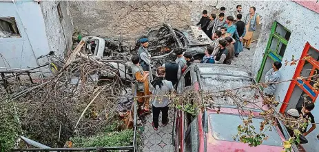  ?? Foto: Profimedia.cz ?? Místo činu Afghánci postávají u ohořelého vraku na dvorku, kam udeřil útok amerického dronu.