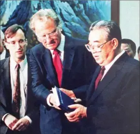  ??  ?? Billy Graham (centre), the US evangelist, presents his book
Korean President Kim Il-sung during a visit to Pyongyang on April 2, 1992. to North