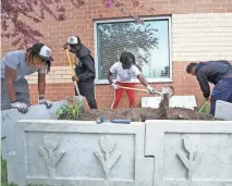  ?? MIKE CARDEW/ AKRON BEACON JOURNAL ?? Buchtel CLC masonry students, from left, Jequelen Harrell, Ryen Finney-Kimble, Wylie Chears and Zyaire Lewis, all 18, work together to install the the back two pieces of a planter at Helen Arnold CLC Wednesday.