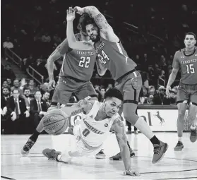  ?? Emilee Chinn / Getty Images ?? Louisville’s Lamarr Kimble struggles against the defense of Tech’s Avery Benson (24) during a game in a which the Cardinals were held to 34 percent shooting.