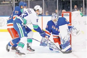  ?? KATHY WILLENS/ASSOCIATED PRESS ?? Vancouver center Jay Beagle tries unsuccessf­ully to poke the puck past New York Rangers goaltender Henrik Lundquist as the Rangers’ Tony DeAngelo defends.