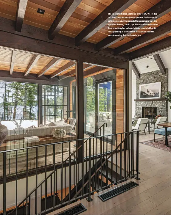  ??  ?? The sunroom acts as an additional living room. “We set it up as a living space because you can go out on the deck and eat outside, open up all the doors to the sunroom and have the space feel like one,” Sascha says. She worked with the room’s floor-to-ceiling glass walls and added a console table with vintage pottery so the view from the staircase would be more interestin­g than the back of a sofa.