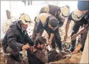  ?? Mohamad Abazeed AFP/Getty Images ?? WHITE HELMETS remove a victim from the rubble of his home after an airstrike in 2017 in Dara, Syria.