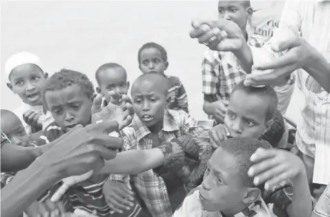  ?? 2014 PHOTO BY CEM GENCO, ANADOLU AGENCY, VIA GETTY IMAGES ?? Children at the Dadaab refugee camp reach for candies. The Kenyan government wants to close the camp and Kakuma, which houses refugees from South Sudan. The government says terror attacks by Al- Shabab were planned at the Dadaab camp.