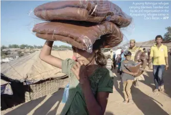  ?? — AFP ?? A young Rohingya refugee carrying blankets handed out by an aid organisati­on in the Kutupalong refugee camp in Cox’s Bazar.