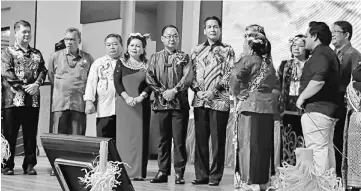  ??  ?? Dennis (sixth left) and Chukpai on his right observe the traditiona­l welcome ritual led by a Kayan elder.