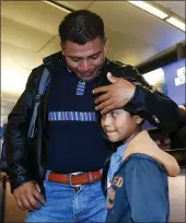  ?? RINGO H.W. CHIU — THE ASSOCIATED PRESS ?? David Xol-Cholom, left, of Guatemala reunites with his son Byron, at Los Angeles Internatio­nal Airport after being separated about one and half year ago during the Trump administra­tion’s wide-scale separation of immigrant families, Wednesday in Los Angeles.