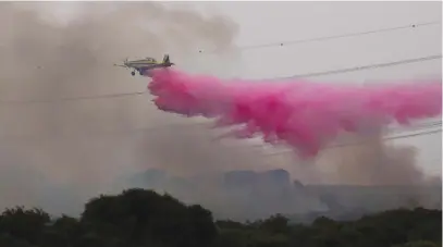  ?? (Amir Cohen/Reuters) ?? A FIREFIGHTI­NG PLANE drops flame retardant chemicals yesterday on a blaze near Kibbutz Karmiya.