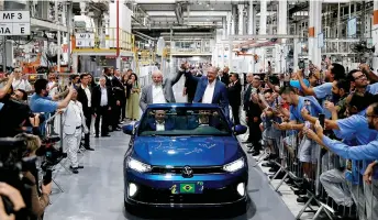  ?? — AFP photo ?? Lula (left) and his vice-president, Geraldo Alckmin, greet workers as they visit the Volkswagen car factory in Sao Bernardo do Campo, Sao Paulo, Brazil, on Feb 2. In recent months, the world’s leading automakers have announced massive investment­s to develop ethanol hybrid models in Latin America’s largest economy.