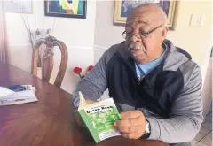  ?? RUSSELL CONTRERAS/ASSOCIATED PRESS ?? Charles Becknell Sr. holds a copy of the 1954 edition of “The Negro Motorist Green Book” at his home in Rio Rancho in January. Becknell grew up in segregated Hobbs and recalls entering some restaurant­s from the back.