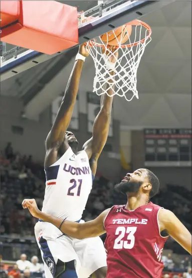  ?? Stephen Dunn / Associated Press ?? UConn’s Mamadou Diarra, left, dunks over Temple’s Damion Moore in the first half on Wednesday in Storrs.