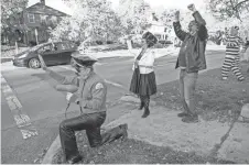  ??  ?? From left, Doug Yost, Brenda Arnold, Fes Minck and Andrew Littlefield wave at passing cars outside the house of Arnold along North Broadway on Oct. 16. The group is out every day in October to help spread Halloween fun.