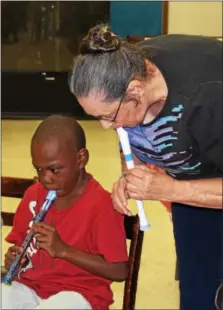  ?? MICHILEA PATTERSON — DIGITAL FIRST MEDIA ?? Music teacher Phyllis Mitchell shows children how to play a note on the recorder during a free music program.