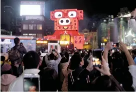  ?? — AFP ?? People take photograph­s of a pig- shaped LED light decoration during the weeklong Taipei Lantern Festival. The annual Lantern Festival will be marked on February 19, which is the 15th day of the Lunar New Year.