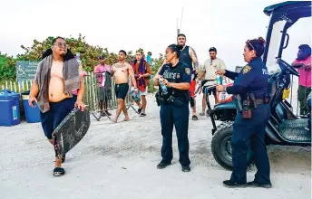  ?? ?? Tourists leave the beach a er Miami Beach police closed access on South Beach.