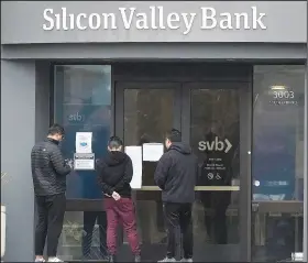  ?? (File Photo/AP/Jeff Chiu) ?? People look at signs posted outside an entrance to Silicon Valley Bank on March 10 in Santa Clara.