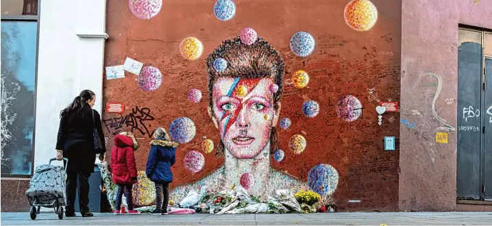  ?? Foto: Wolfram Kastl, dpa ?? In aller Welt berühmt: das Wandbild unweit des Geburtshau­ses von David Bowie in London. Es zeigt ihn als Glamrocker mit knallroten Haaren und Blitz im Gesicht. Das Bild wurde 2016 zu einer Art Schrein für trauernde Fans.