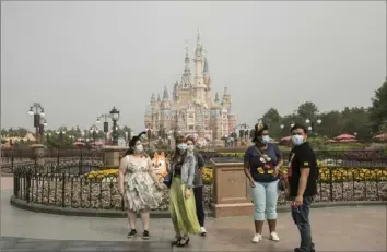  ?? Qilai Shen/Bloomberg ?? Visitors wearing protective masks stand in front of the Enchanted Storybook Castle during the reopening of Shanghai Disneyland theme park in Shanghai on Monday.
