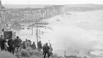  ?? — AFP photo ?? People gather uphill to watch waves crash on the seafront of Wimereux, northern France, as Storm Eleanor hits the northern part of France.