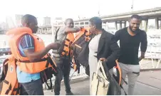  ?? ?? Officials of state-run ferries, Lagos State Waterways Agency (LASWA), collects a life jacket from a passenger on arrival on board a ferry at Falomo jetty in Lagos.